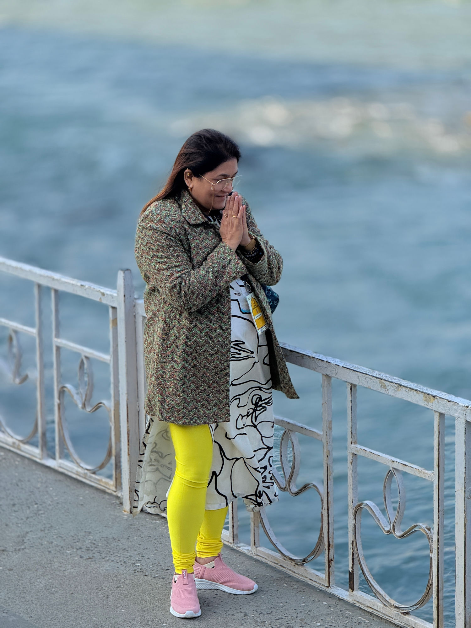Reshma Pathare standing beside the water, hands folded in namaste.